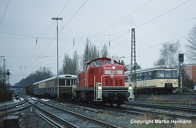 Am 6. Februar 2001 brachte 291 037 den Museumszug von Neumünster nach Hamburg zurück. Um 10.44 Uhr trafen beide im Güterbahnhof Barmbek direkt am Haltepunkt Alte Wöhr ein, den gerade 470 116 in Fahrtrichtung Hauptbahnhof passierte.